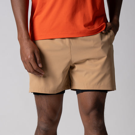 Gray background, close up of the JOOLA Men's 2 in 1 shorts, latte color.