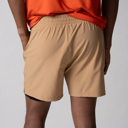Gray background, close up image of the back of a male model wearing a pair of JOOLA Men's 2 in 1 shorts, latte color.