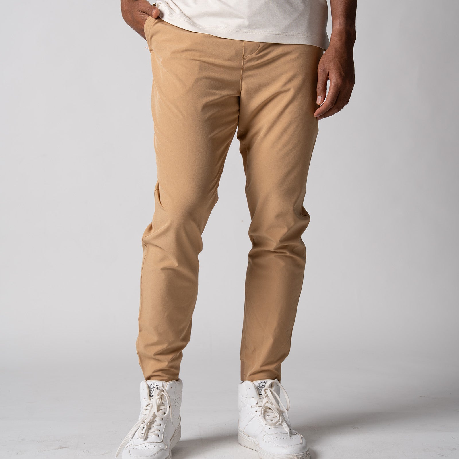 Gray background, close up image of a male model wearing a pair of JOOLA men's club joggers, latte color.