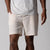 Gray background, close up image of a male model wearing a pair of JOOLA men's club shorts, sandstone color.