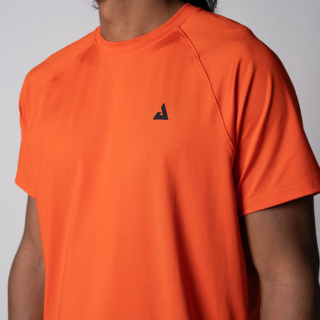 Gray background, close up image of the black trinity logo over the left chest of the JOOLA Men's Court Short Sleeve tee in poppy red.