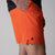 Gray background, close up of a black JOOLA trinity logo on the right leg of a pair of Men's Woven Short, poppy red.