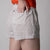 Gray background, close up on the back of a female model with her hand in the back pocket of a pair of JOOLA Women's Court Woven Printed Shorts.