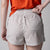 Gray background, female model wearing the JOOLA women's court woven printed shorts.