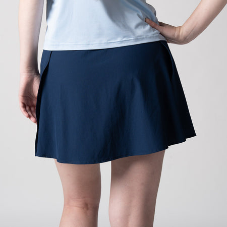Gray background, image of a female model wearing a JOOLA women's pickleball skort, navy.