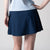 Gray background, image of a female model wearing a JOOLA women's pickleball skort, navy.