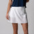Gray background, image of a female model wearing a JOOLA women's pickleball skort, white.