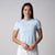 Gray background, female model wearing a JOOLA women's club short sleeve, blue breeze.