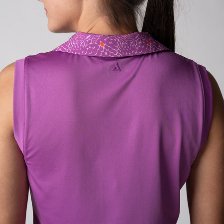 Gray background, image of the back of a female model wearing a JOOLA women's club sleeveless polo, purple passion.