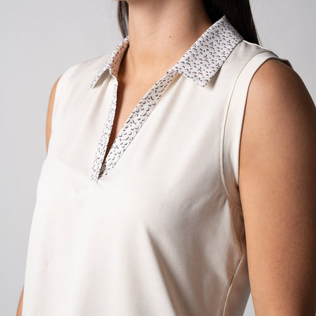 Gray background, close up image of the collar on a JOOLA women's club sleeveless polo, sandstone and print.