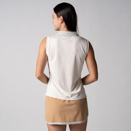 Gray background, female model wearing a JOOLA women's club sleeveless polo, sandstone color.