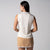Gray background, female model wearing a JOOLA women's club sleeveless polo, sandstone color.