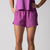 Gray background, female mode wearing a pair of JOOLA women's court woven shorts, passion purple.