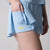 Gray background, close up on the hidden under short pocket and yellow JOOLA word mark on the JOOLA women's pickleball skort, blue breeze.
