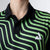 Person wearing a black and green striped shirt with a logo on a plain background