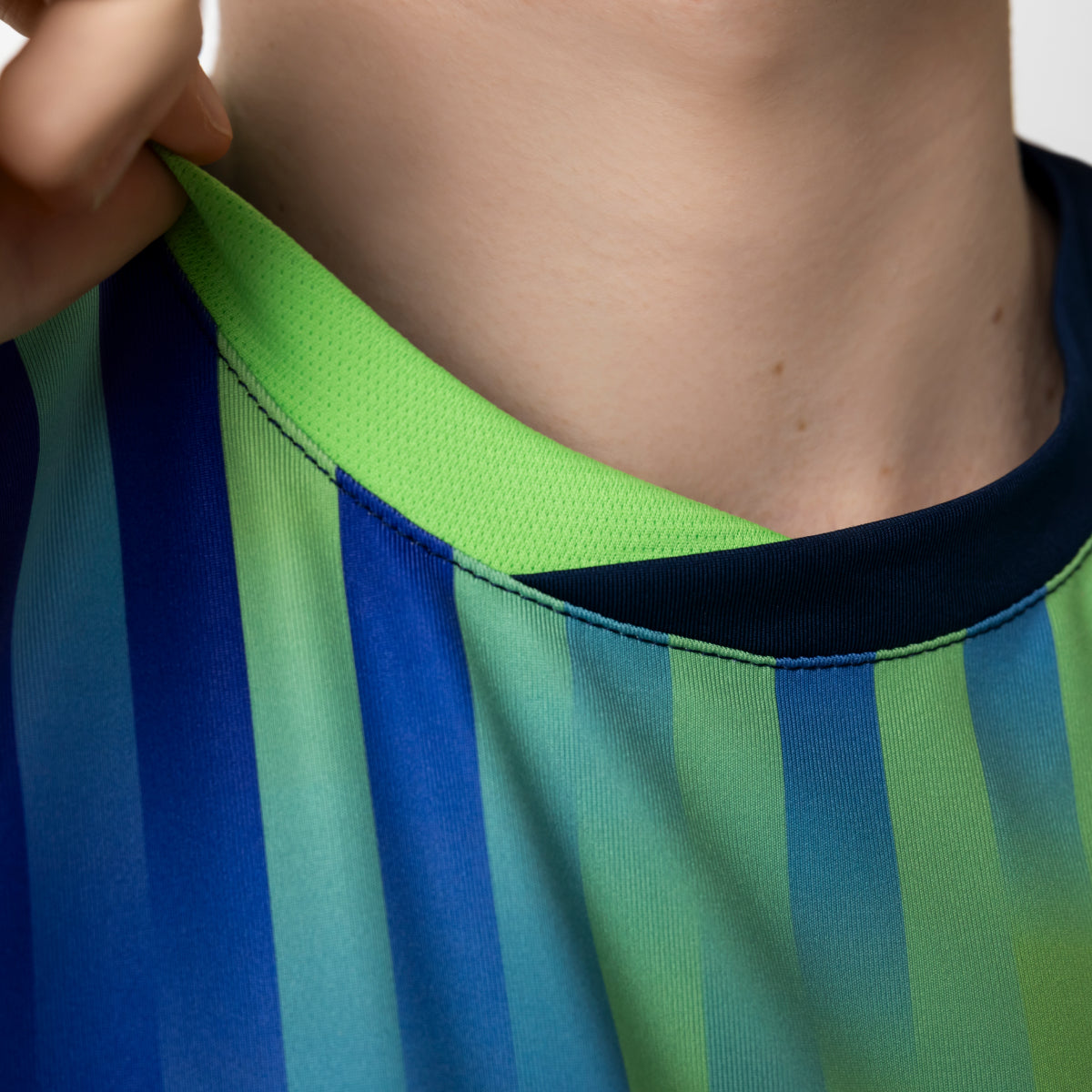 Close-up of a person wearing a blue and green striped shirt with a hand adjusting the collar.