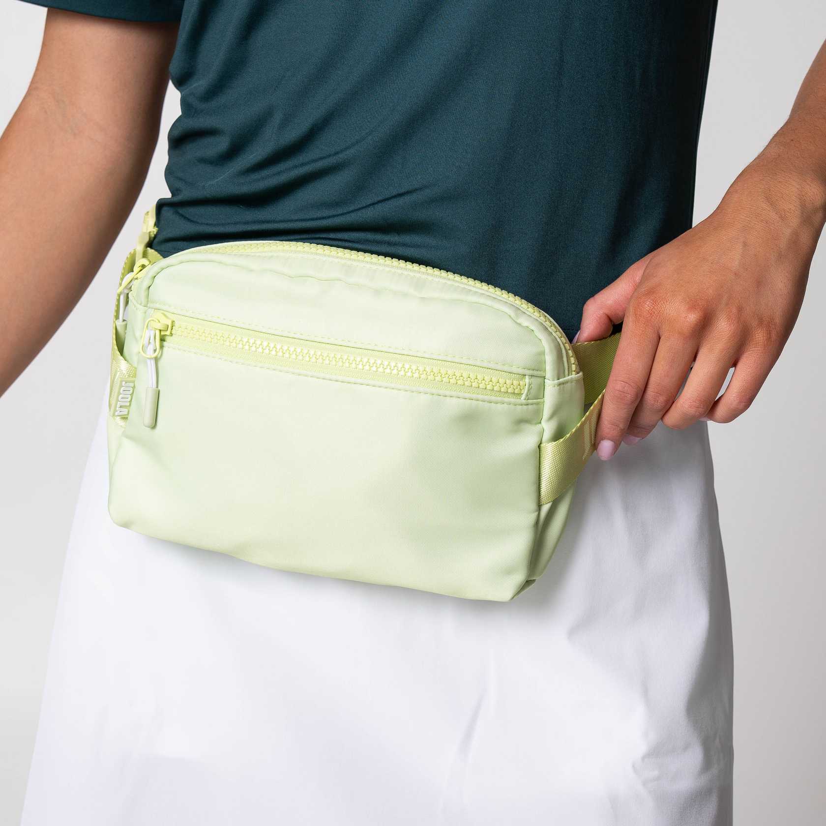 Gray background, image of a Key Lime JOOLA Belt Bag around a models waste.