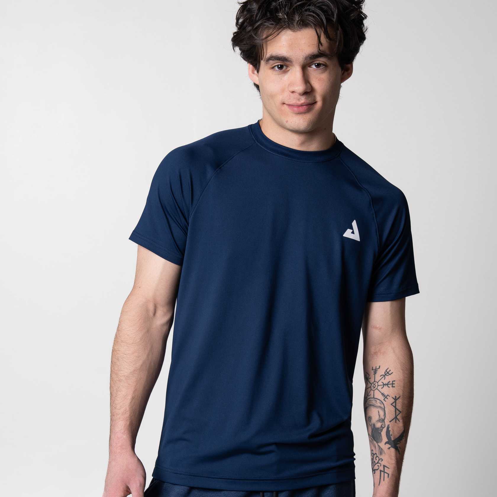 Gray background, image of a model wearing the navy blue JOOLA Short Sleeve shirt.