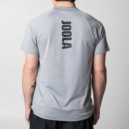 White background, image of the JOOLA logo running down the center of the back of a JOOLA Court Short Sleeve Shirt, Gray.