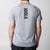 White background, image of the JOOLA logo running down the center of the back of a JOOLA Court Short Sleeve Shirt, Gray.
