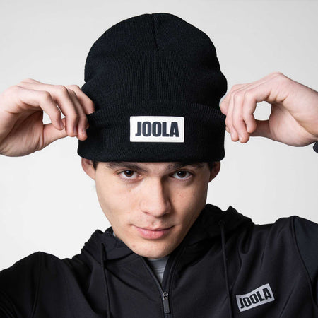 Close up on the white and black JOOLA logo on a black JOOLA Cuff Beanie.
