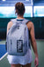 Person wearing a gray backpack with 'JOOLA' logo on a pickleball court.