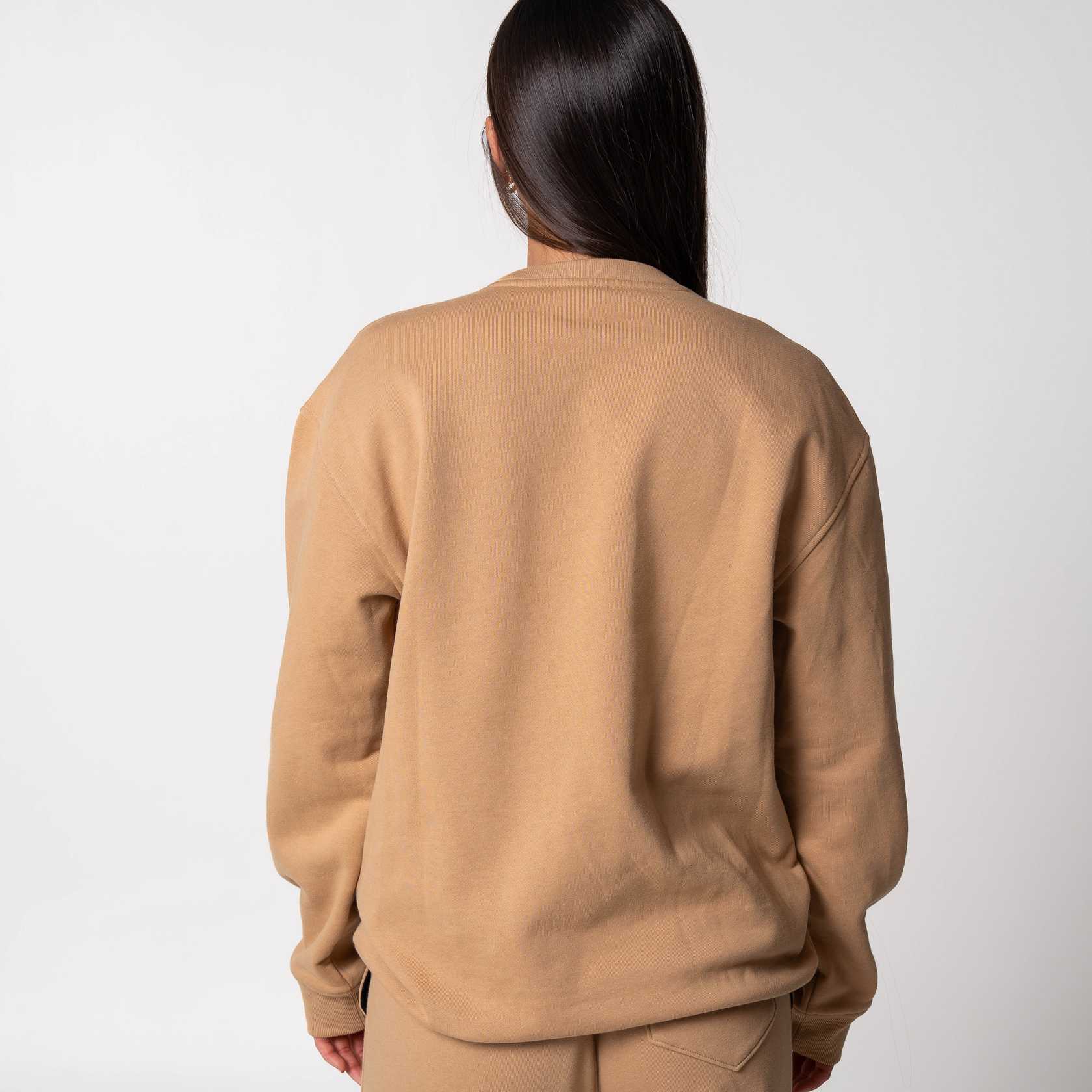 Gray background, image of the back of a female model wearing a fleece crew, latte.