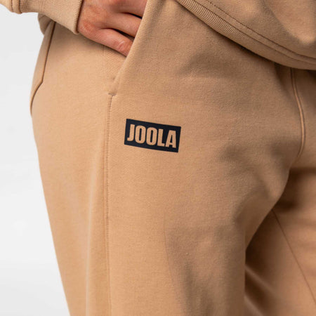 Close up on the JOOLA logo on a pair of JOOLA Fleece Pants, Latte.