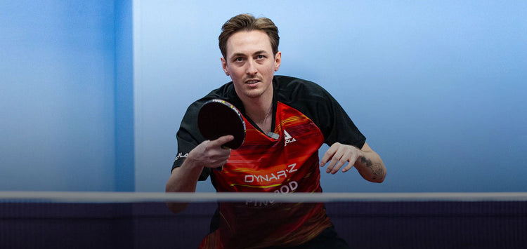 Person playing table tennis with a blue background