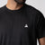 Close up of the JOOLA Trinity logo above the left chest of the JOOLA Men's Court Short Sleeve Shirt, Black.