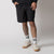 Male model wearing a pair of JOOLA Men's Woven Shorts with a Nine-Inch inseam, black.