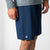Side profile image of a male model wearing a pair of JOOLA Men's Woven Shorts with a Nine-inch inseam, navy.
