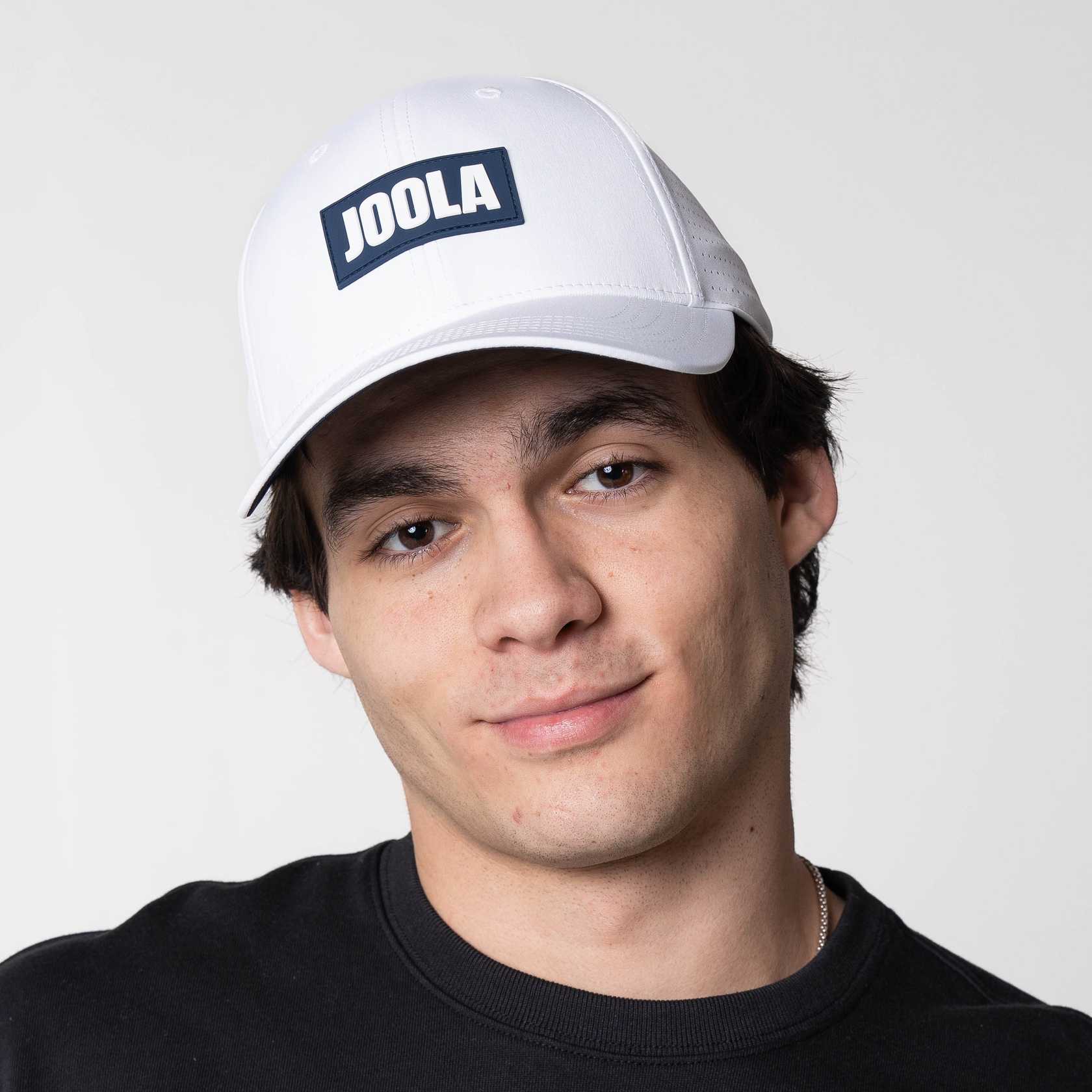 Male model posing in the JOOLA Perforated White Cap, White and Blue.