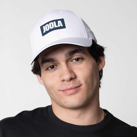 Male model posing in the JOOLA Perforated White Cap, White and Blue.