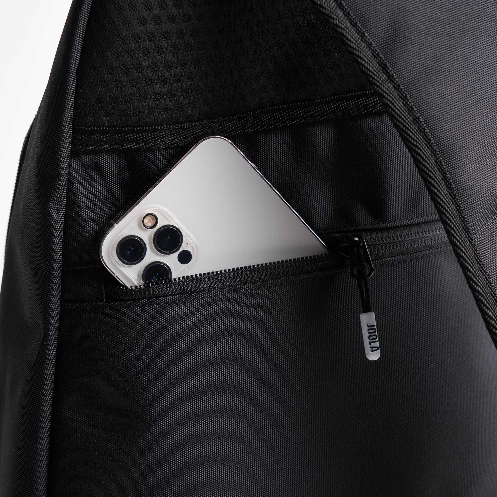 Close up image of a cell phone in the side pocket of a JOOLA Sling Bag, black.