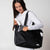 Gray background, Image of a female model putting a JOOLA Pro IV paddle in the front pocket of here JOOLA Tote bag.