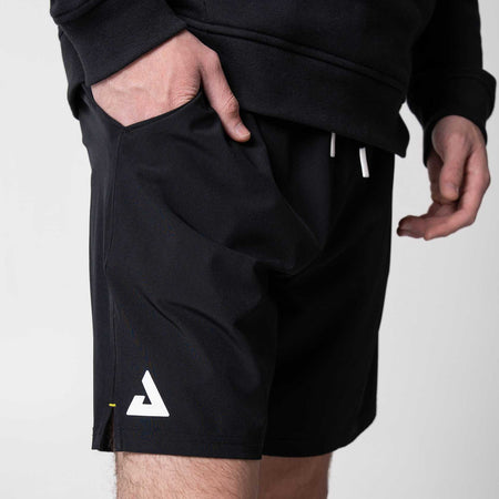 Close up on the white JOOLA Trinity logo on a pair of JOOLA Woven Shorts, black with 7-inch inseam.