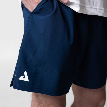 Close up on the white JOOLA trinity logo on the leg of a pair of Navy blue JOOLA Woven shorts, 7-inch inseam.